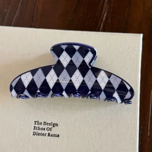 Gros plan d'une pince à cheveux élégante en acétate avec motif argyle bleu marine.