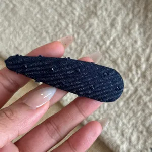 Gros plan sur une pince à cheveux en tissu denim bleu foncé avec une texture douce et élégante.