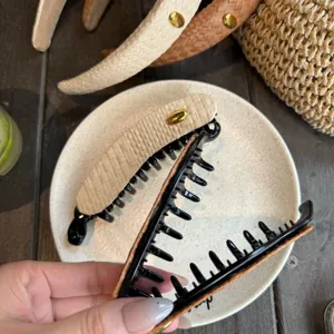 Vue détaillée de la pince banane tissée avec un accent en métal doré et des dents robustes.