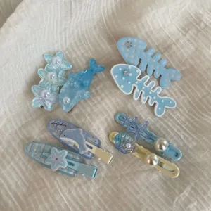 Cute blue marine hair clips detail featuring dolphins, starfish, shells, and sparkling pearls.