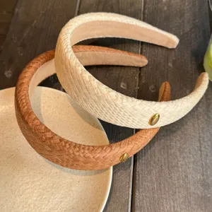 Gros plan détaillé de serre-têtes tressés élégants en raphia avec boutons dorés.