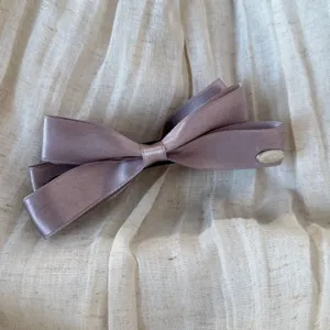 Dettaglio fermaglio per capelli in nastro di satin, fiocco malva elegante con targhetta.