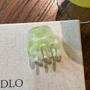 Détail de pince à cheveux en acétate vert, petit accessoire marbré pour coiffure élégante.