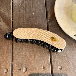 Détail de pince à cheveux banane tissée exquise avec élégant accent en métal doré.