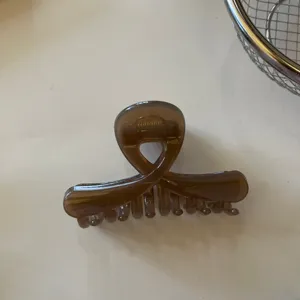 Dettaglio in primo piano della molletta per capelli marrone lucida con molla in metallo.