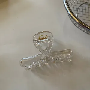 Molle per capelli trasparente in acrilico con design incrociato e molla dorata elegante.