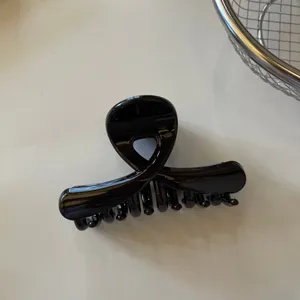 Primo piano di un morsetto per capelli nero lucido incrociato, con finitura elegante e liscia.