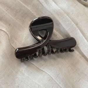 Primo piano dettagliato di un morsetto per capelli marrone scuro lucido su sfondo in tessuto.