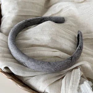Elegante fascia per capelli in tessuto grigio scuro con motivo discreto, accessorio quotidiano.