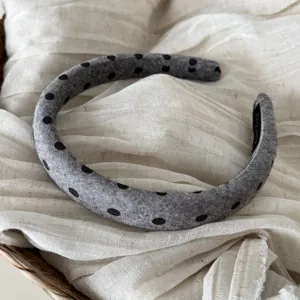 Dettaglio del cerchietto imbottito grigio a pois, che mostra la morbida consistenza.