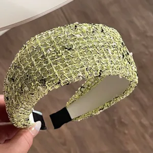 Detailed view of wide woven tweed headband in light green with black and white texture.