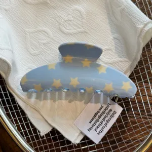 Primer plano detalle del gancho para el pelo de acetato azul con patron de estrellas.
