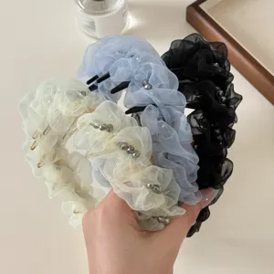 Vue détaillée de serres-tête en tissu plissé avec perles délicates, style élégant et doux.