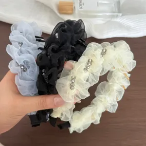 Détail du serre-tête en gaze à bulles avec perles de cristal et dents longues.