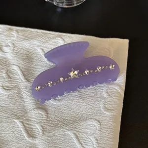 Primo piano di un fermaglio per capelli viola opaco decorato con strass lucidi a stella.