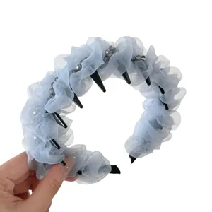 Serre-tete plisse en organza bleu clair avec dents et perles pour coiffure elegante de femme.