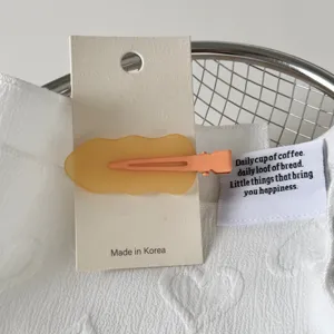 Close up detail of the cute macaron yellow wavy hair clip presented on cardboard.