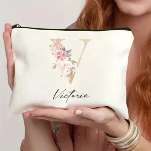 Detalle de neceser de maquillaje personalizado con letra floral y cierre de cremallera.