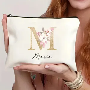 Detalle del neceser de maquillaje personalizado en blanco con inicial dorada y flores.