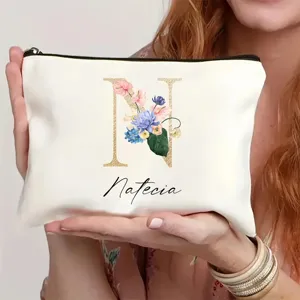 Detalle de neceser de maquillaje blanco personalizado con letra floral N y texto de nombre.