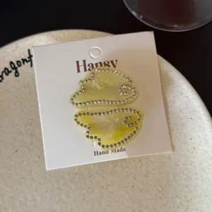 Close-up detail of acetate hair clip featuring glittering rhinestones on card, chic accessory.
