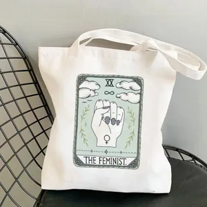 Close-up detail of a white canvas tote bag featuring a tarot card style feminist art print.