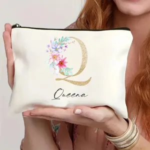 Detalle en primer plano de bolsa de cosméticos blanca con letra floral Q y nombre.