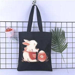 Black canvas tote bag detail showing the cute rabbit and egg print design for daily student use.
