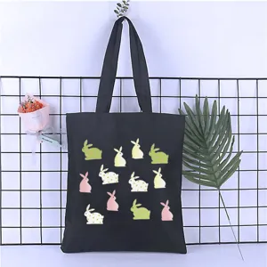 Detail view of black canvas tote bag featuring cute cartoon rabbit prints and sturdy shoulder straps.
