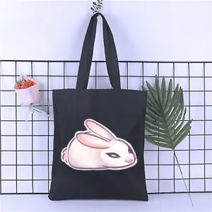 Detailed view of a black canvas tote bag featuring a cute white rabbit print and durable straps.