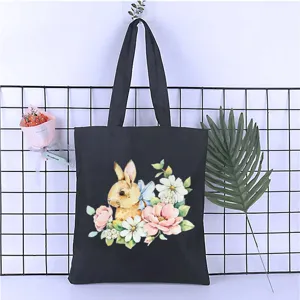 Close-up of the delicate watercolor rabbit and floral print on a durable black canvas tote bag.
