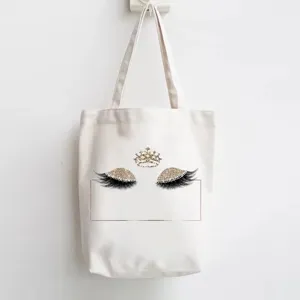 White canvas tote bag with stylish glitter eyelash and crown print for daily shopping.