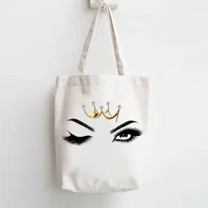 Canvas tote bag with cute wink eye and crown print, stylish and durable everyday shoulder bag.
