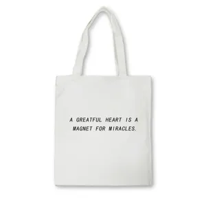Close-up detail of white canvas tote bag featuring motivational English quote print.