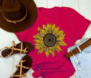 Close-up detail of a vibrant pink short-sleeve t-shirt featuring a detailed sunflower graphic print.
