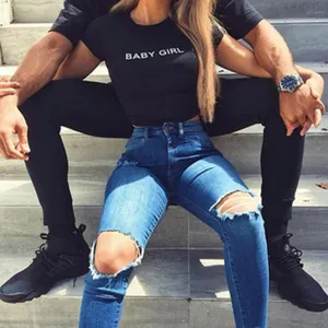 Women fashion black crop top with baby girl letter print and blue ripped skinny jeans.