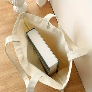Detailweergave van de canvas tote tas met grote capaciteit en een boek erin voor opslag.