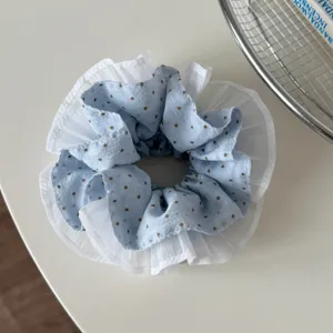 Closeup of light blue polka dot hair scrunchie with delicate white ruffled edge detail.