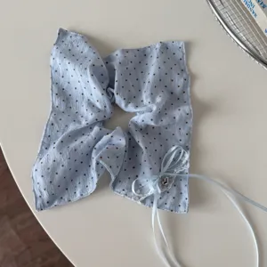 Close up of blue polka dot hair scrunchie featuring delicate lace trim and ribbon bow.