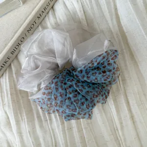 Detail view of the two-tone sheer scrunchie, showcasing white and blue leopard mesh.