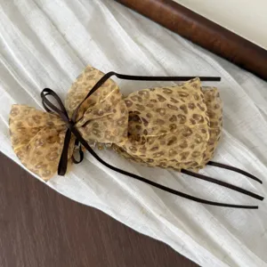 Detailed close-up view of a chic leopard print mesh hair bow clip adorned with brown ribbons.