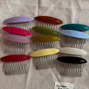 Close-up detail shot of colorful oval acetate hair combs with metal teeth for elegant styling.