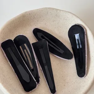 Closeup view of black fabric geometric hair clips set neatly arranged on a textured ceramic plate.