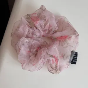 Detailopname van de roze bloemige organza haarscrunchie, lichtgewicht stof en fijne print.