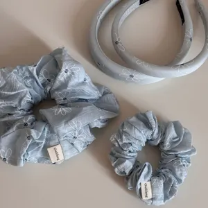 Close-up detail of light blue floral daisy hair scrunchies and headbands fabric texture.