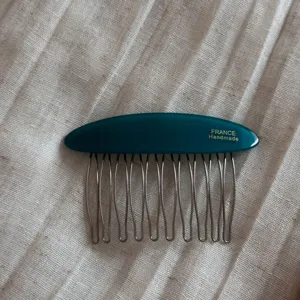 Detail view of acetate insert hair comb featuring metal tines and smooth dark green finish.