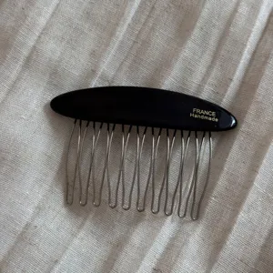 Detailed close-up of the black oval insert hair comb, featuring metallic teeth and text detail.