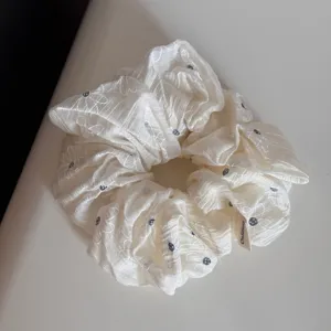 Oversized white floral hair scrunchie detail shot, soft fabric daily hair accessory.