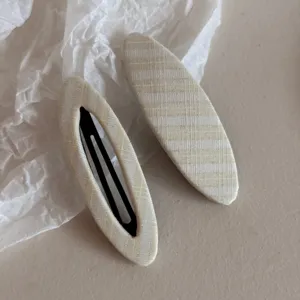 Dettaglio fermaglio capelli in tessuto scozzese, texture morbida molletta beige, accessorio