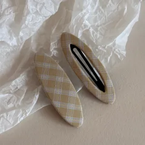 Primo piano dell'elegante fermaglio per capelli in tessuto scozzese, accessorio chic per donna.